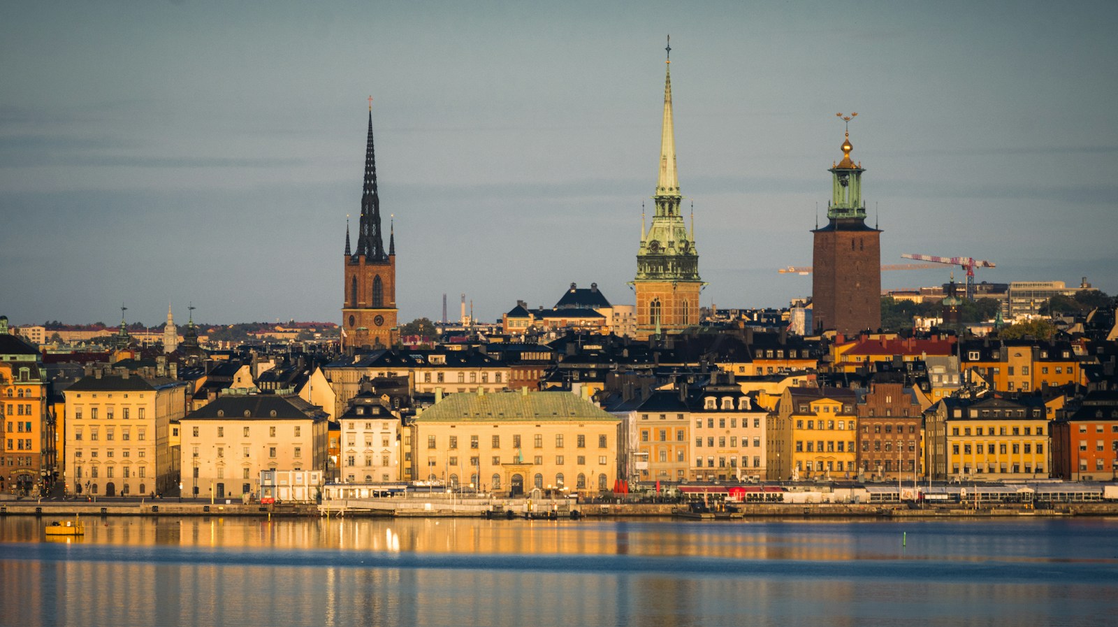The Stockholm waterfront skyline with the Riddarholmen spire and City Hall tower at golden hour