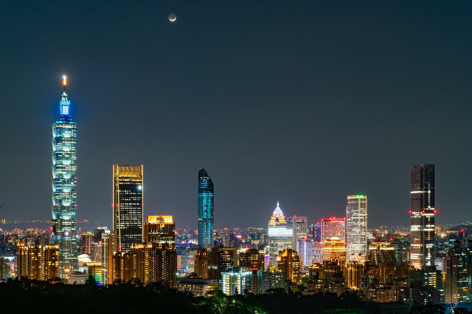 The Taipei 101 tower lit up above the Taipei skyline at night