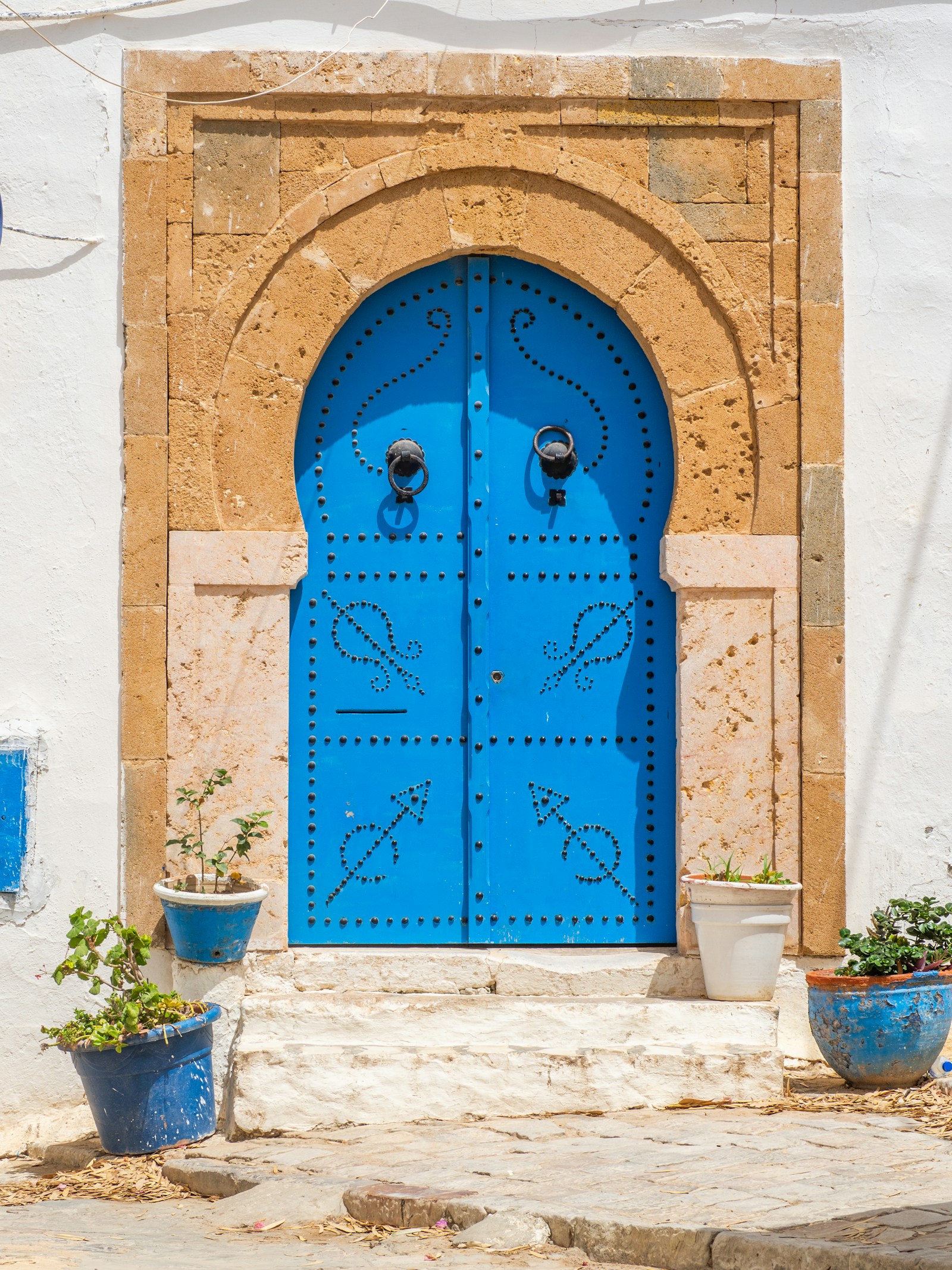 A traditional blue studded door in a sandstone arch in Sidi Bou Said, Tunisia