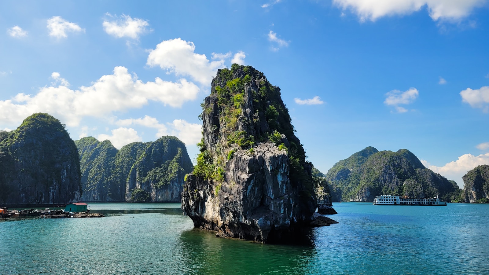 Limestone karsts and a cruise boat on the emerald water of Ha Long Bay